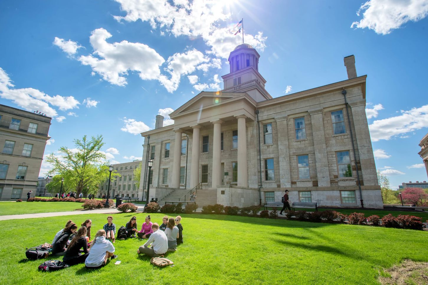Students sit on the grass in front of the Old Capitol enjoying the nice weather i