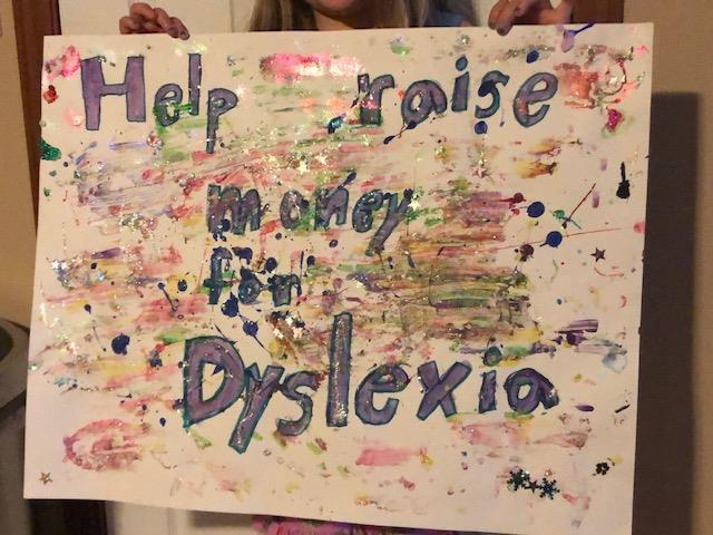 A colorful "Help Raise Money for Dyslexia" sign made by the three girls