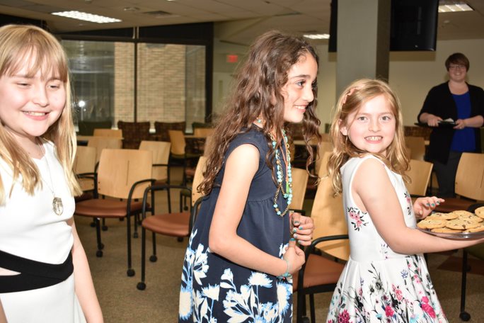 Grace, Sophie, and Talen walking around with cookies during the IRRC celebration ceremony