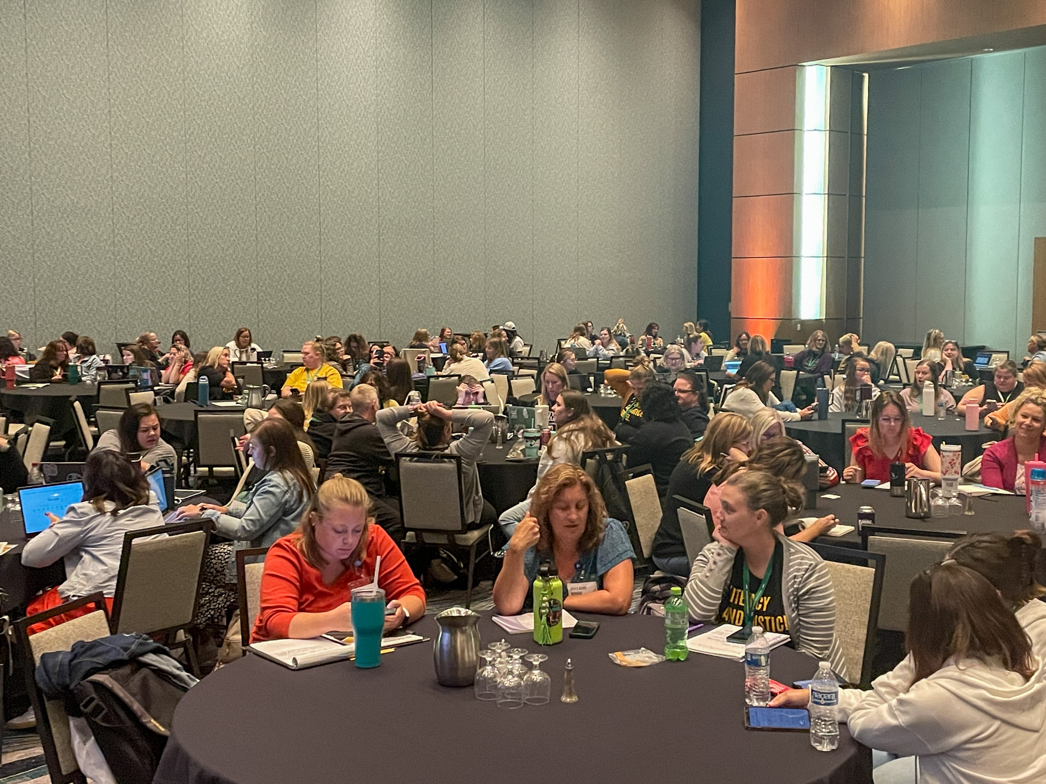 Attendees sit at tables in the main exhibit hall