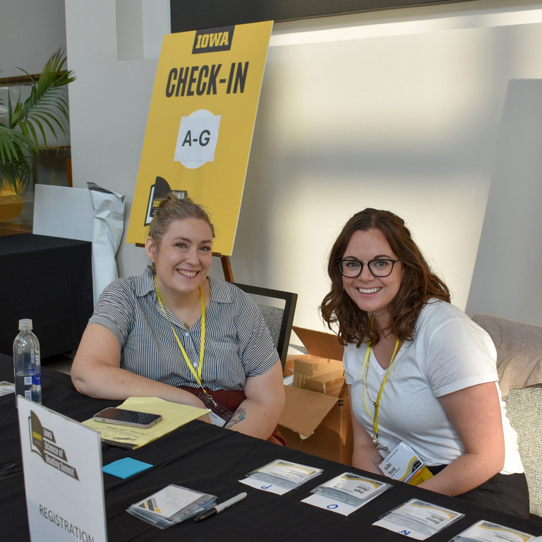 Two IRRC staff members sit at the summit check-in table.