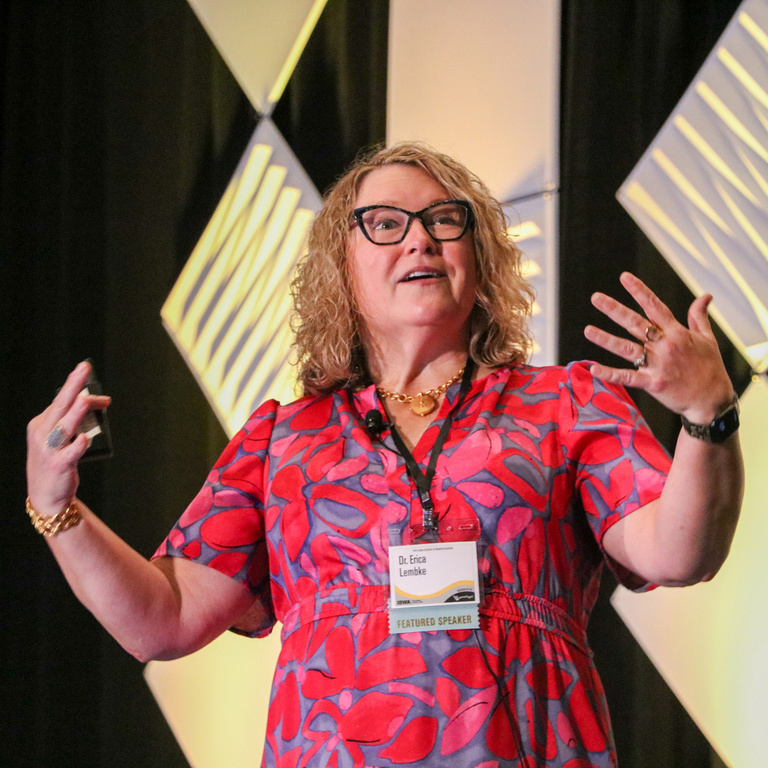 Summit keynote speaker gestures with both arms will presenting on stage.