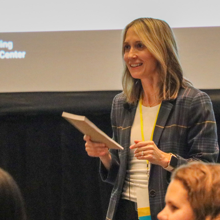 IRRC staff member holds book while presenting a PowerPoint.