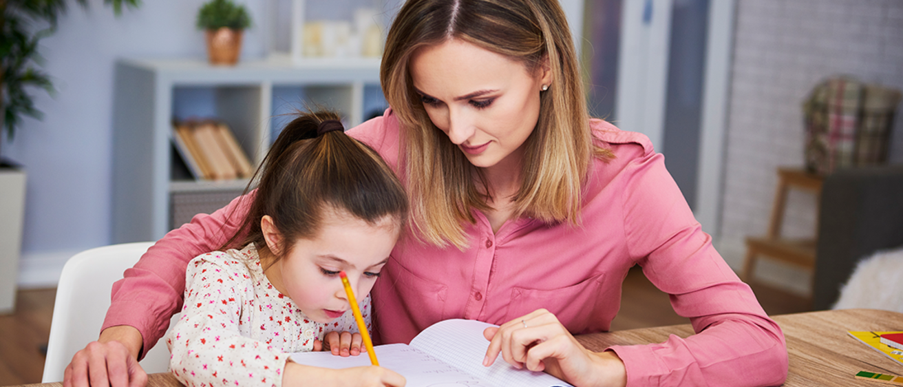 Daughter receiving literacy help from mother at home
