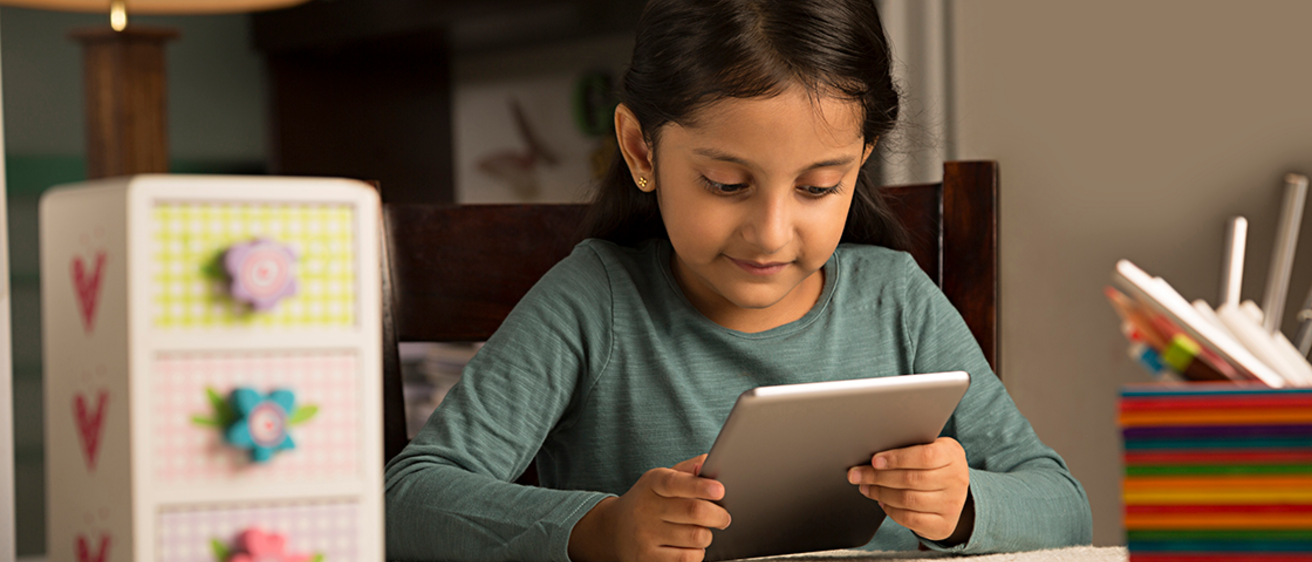 A girl using assistive technology, a tablet, at home to help with homework.