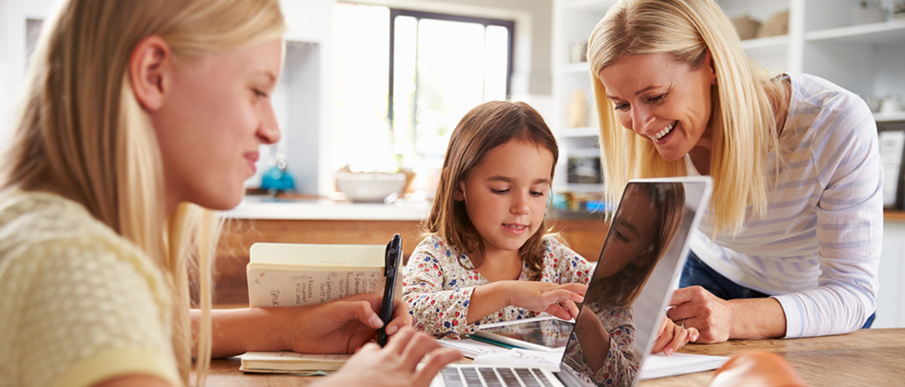 Mother and two daughters learning at home with different devices like tablets and laptops.