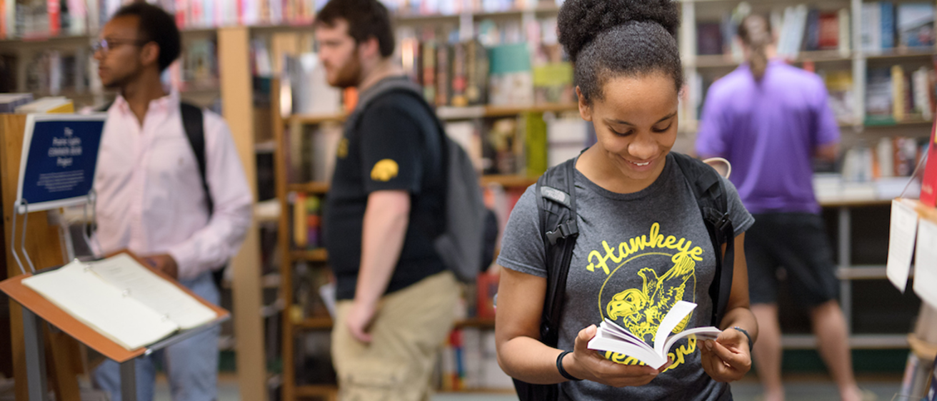 A girl reading a book at a book store, engrossed in reading.