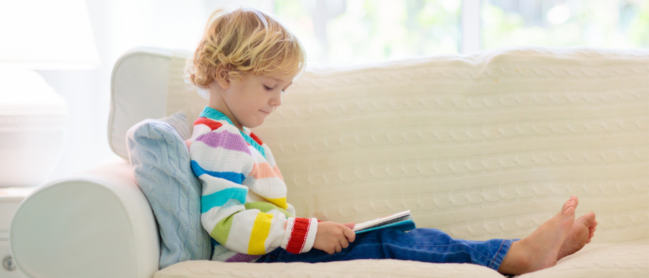 Young kid reading on a couch at home