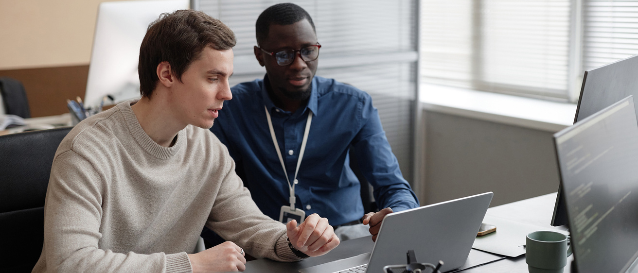 two men work together on a computer