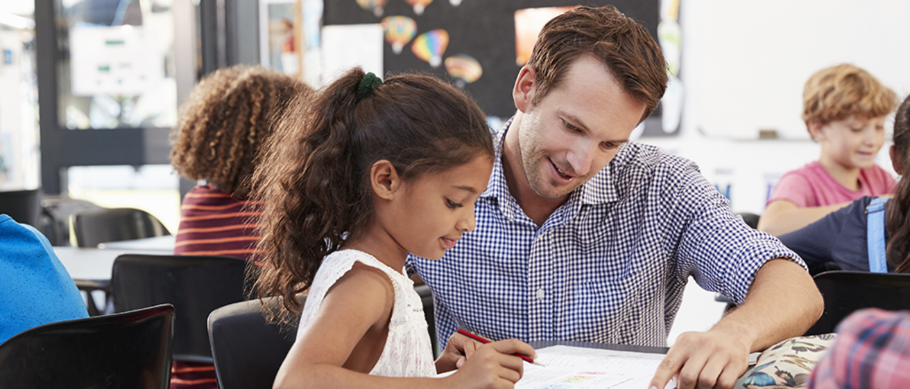 teacher helps student with activity at desk
