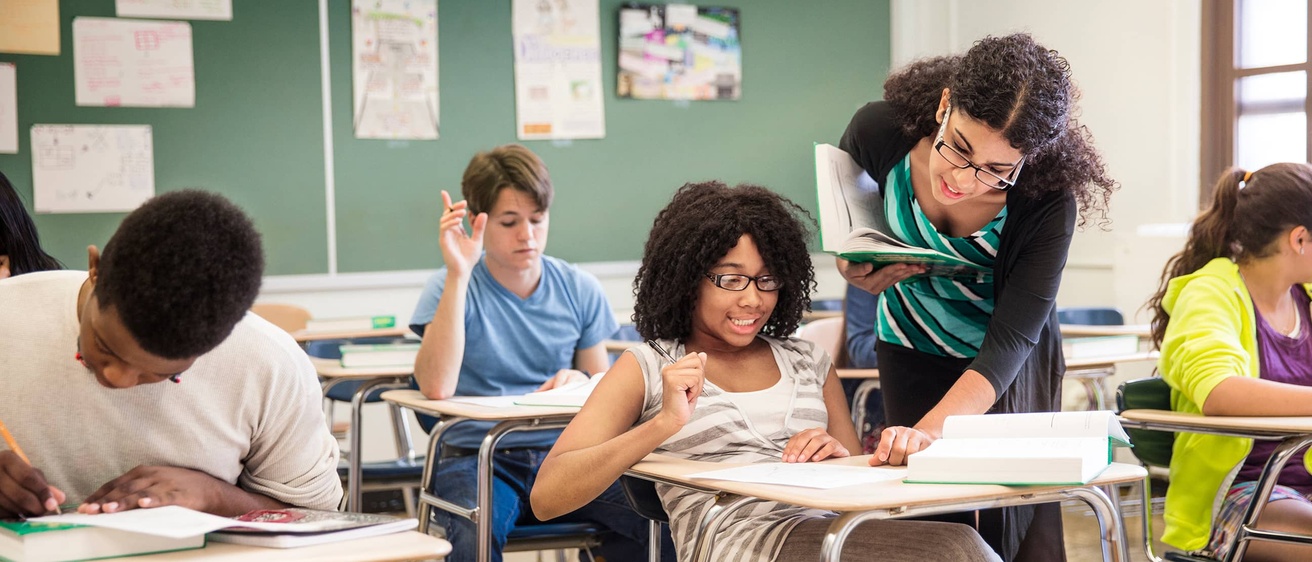A teacher assists a student raising their hand. 