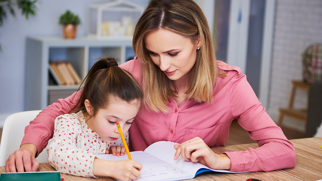 Daughter receiving literacy help from mother at home