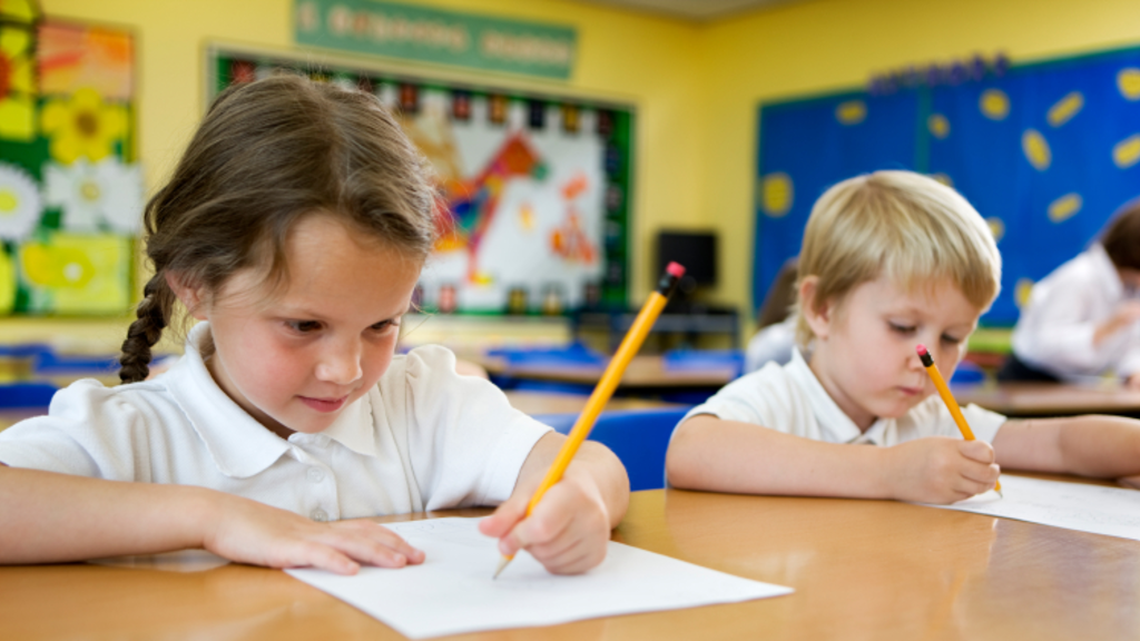 Girl and boy writing on a piece of paper with pencils during class