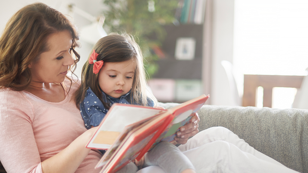 Mother and daughter read on couch together