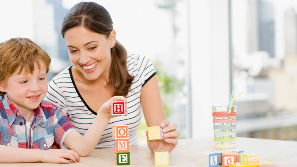 Mother and son playing with letters blocks at a kitchen table during guided play