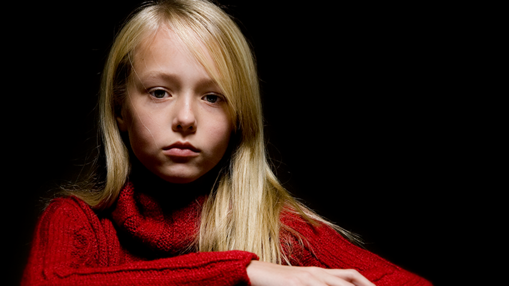 A sad girl in a red sweater with a black background