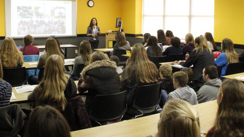 A presenter speaking to a room of people during a student journalism conference workshop