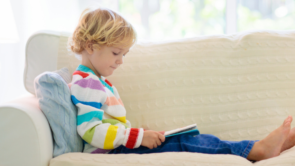 Young kid reading on a couch at home