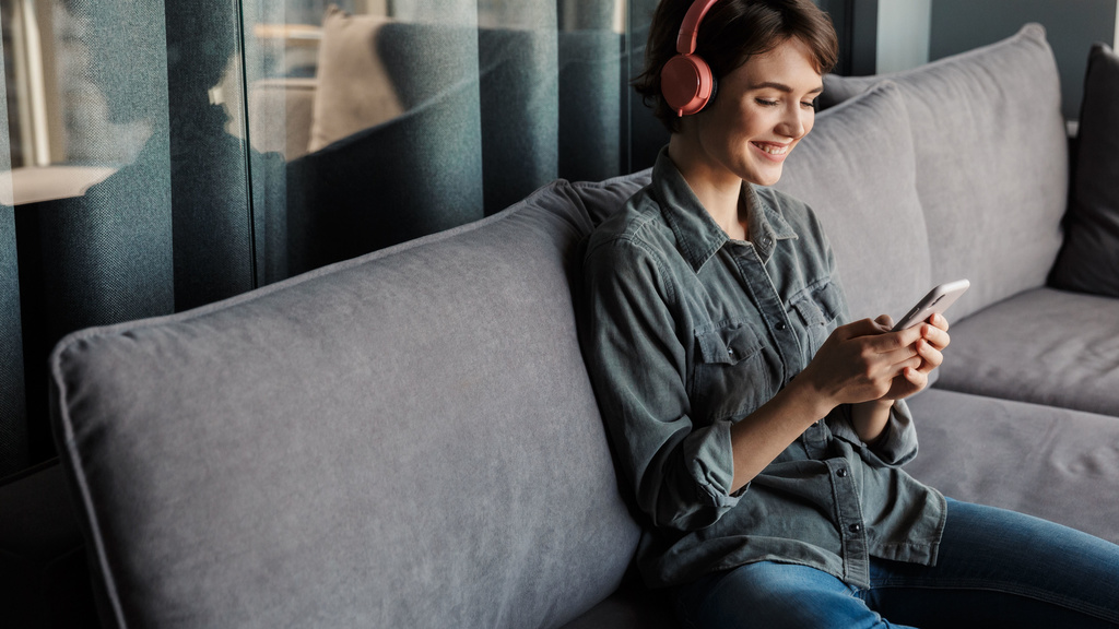A woman sitting on a couch listening to headphones