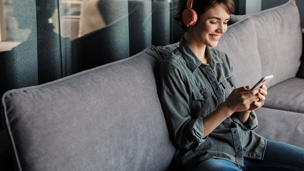 woman sits on a couch with headphones