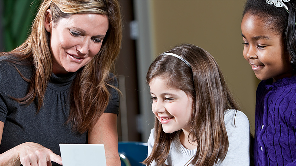 teacher helps two students with flashcard