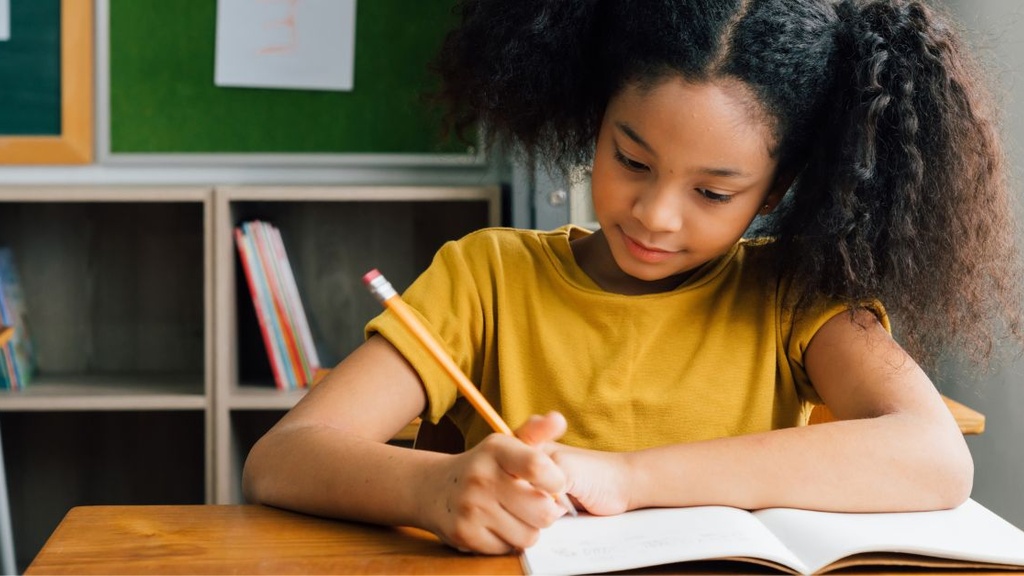 A young girl writing in a book.